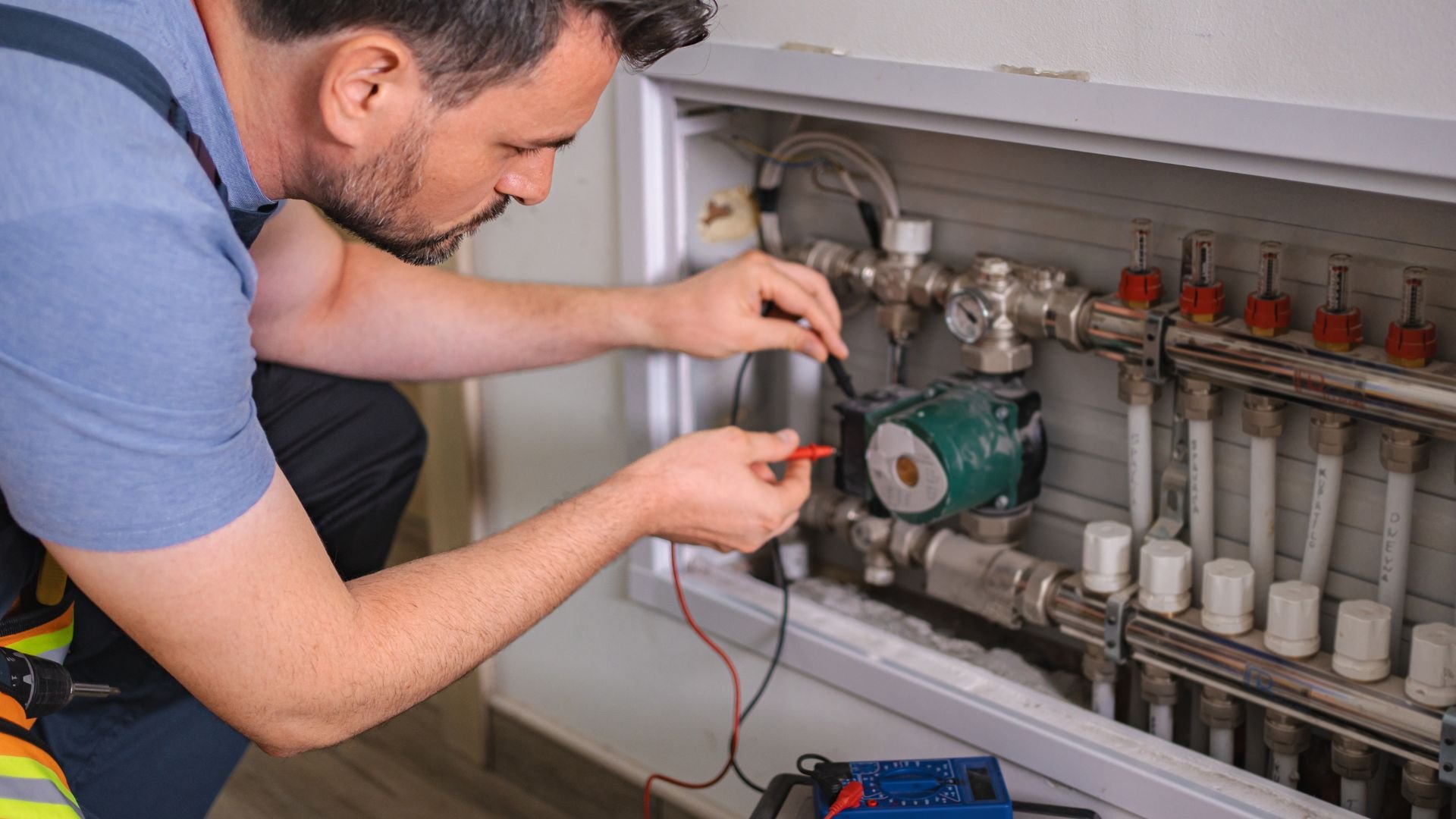 Technician checking electrical connections on heating system manifold
